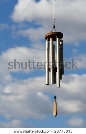 Wind chime with blue sky and clouds visible in background