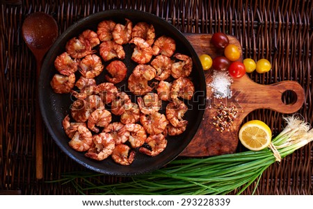 Shrimp fried in soy sauce with garlic in olive oil first press, served in a cast iron skillet, poured lemon juice,Yellow cherry tomatoes and red onions complement the composition with shrimps