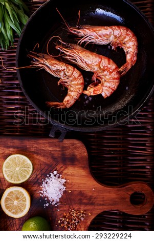 The best snack to beer, prawns, grilled or rapid fire in a deep frying pan. Three large tiger shrimps lie in a deep bowl for dikustatsii near lemon and lime and rosemary