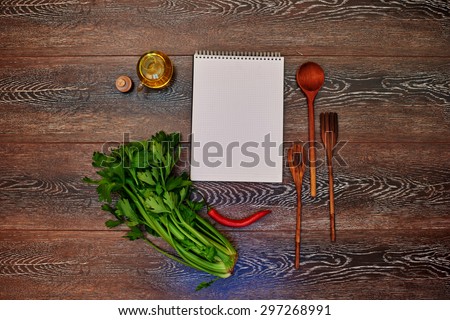 A place for advertising, notebook lying on a wooden table next to the kitchen, wooden cutlery, olive oil, red hot chili peppers