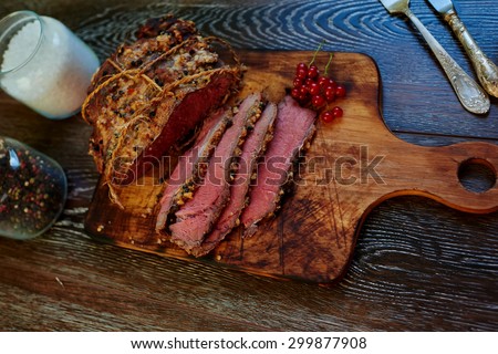 Cook bake in the oven a large piece of pork, well seasoned with spices and aromatic herbs, red meat, for gourmets, near steak are silver cutlery