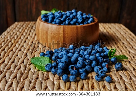 On a small table is a light wicker wooden utensils, decorated with berries, mint leaves