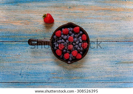 Top view, fresh berries are laid out in a cast-iron skillet to cook them a little bit and make a sweet and delicate dessert