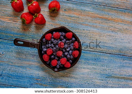 In the kitchen, bakery, cook pan left on the table with berries, side by side on a wooden table lie the few remaining strawberries