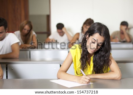 Beautiful brunette student writing an exam