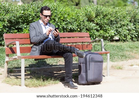 Man sitting on park bench writing on cell phone