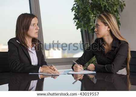 Two businesswomen looking at each other sitting at a table, in the background you can see the skyline of Barcelona