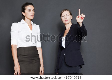 Two business women pointing on a virtual screen