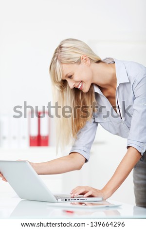 Happy woman standing and browsing the internet through her laptop