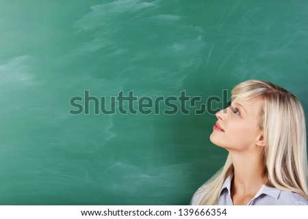 Blond student looking at the green board in classroom