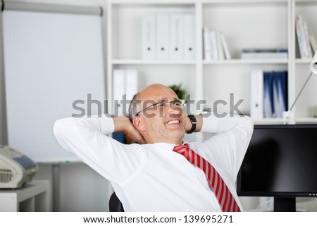 happy businessman leaning back with hands behind his head