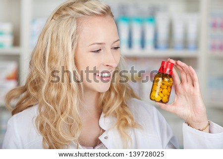 Closeup of happy female pharmacist holding medicine bottle in pharmacy