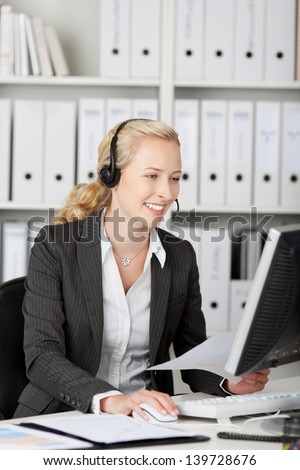 Closeup of female blond customer service executive using headset in office