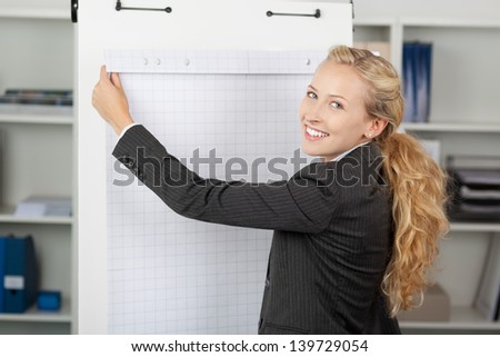 Portrait of young businesswoman with flip chart in office