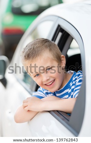 Small young boy in the car smiling and looking out the window