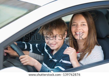 Beautiful mother teaching her son how to drive a car