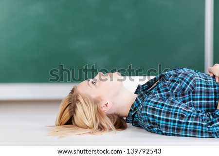 Side view of young female student lying on desk in classroom