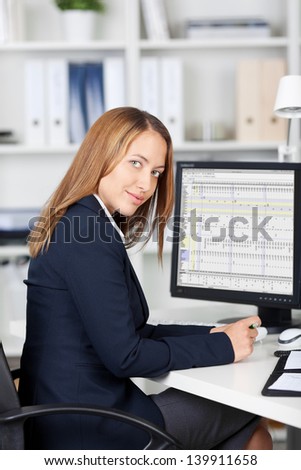 Portrait of confident businesswoman with computer on desk