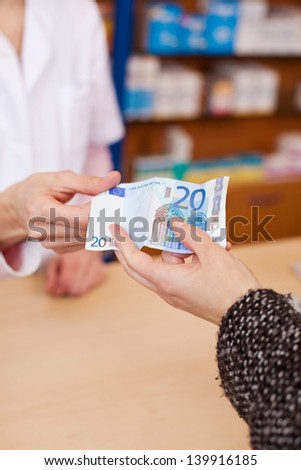 Closeup of customer\'s hand paying money to pharmacist at counter