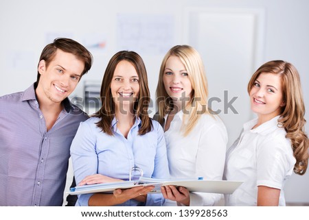 Confident businesspeople with binder standing together in office