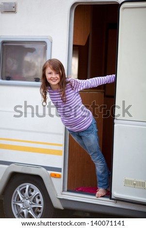 Portrait of playful cute girl standing at caravan entrance