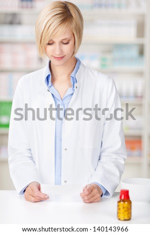 pharmacist reading prescription paper at pharmacy counter