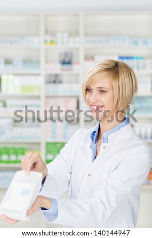 Happy young female pharmacist giving prescription medicines in pharmacy