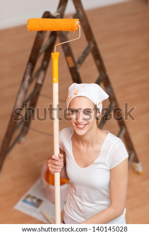 young female painting her house with paint roll