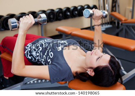 Fitness woman lifting dumbbells and lying in a close up shot