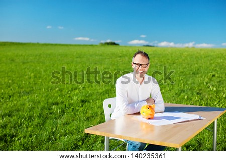 Wise man sitting on the chair with piggybank on his table