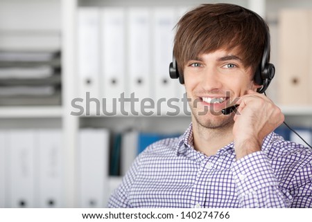 Portrait of handsome customer service executive using headset in office