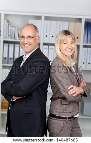 businesspeople with arms crossed standing back to back in office