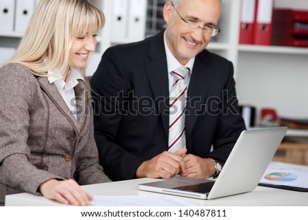 male and female colleagues looking smiling at laptop