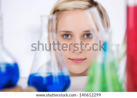 Closeup portrait of young female scientist with chemicals on laboratory desk