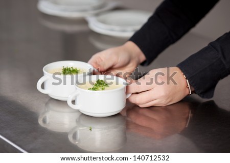 waitressÃ?Â´hand holding soup at restaurantÃ?Â´s kitchen