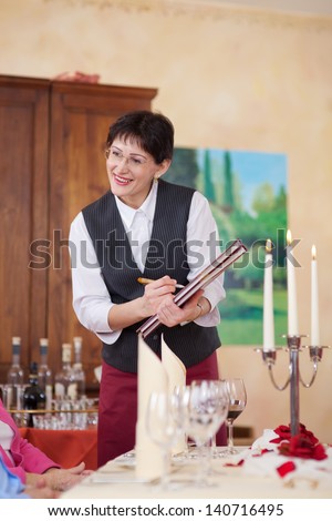 smiling waitress with menu writing the order
