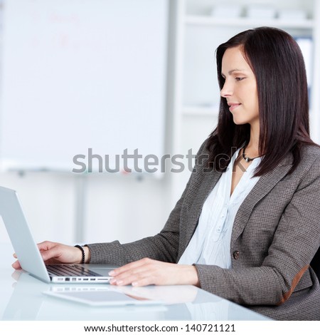 Pretty businesswoman browsing through the laptop in a side view shot