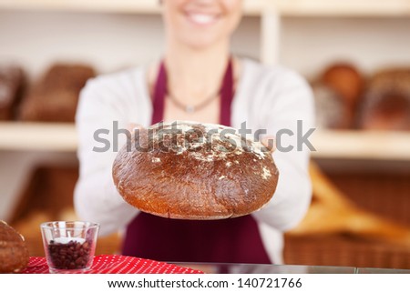 Woman baker holding fresh baked bread in a close up shot