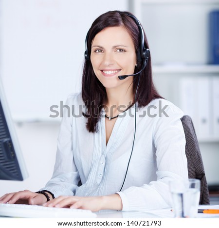 Pretty call center operator typing on the keyboard at her table