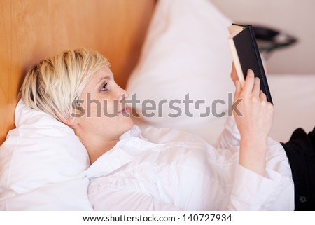 Relaxed young businesswoman reading diary while lying on bed at home