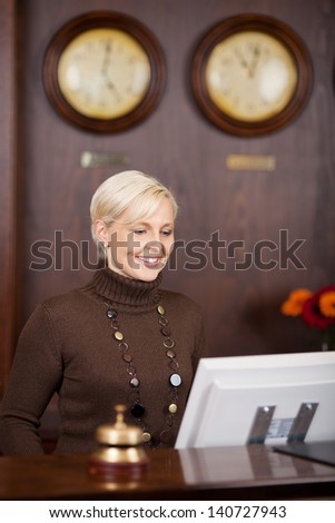 smiling female receptionist working at hotel counter