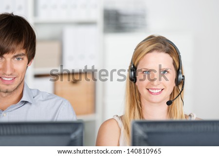 two smiling colleagues with headset in the office