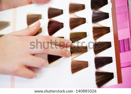 Closeup of client\'s hand choosing color from hair samples in salon