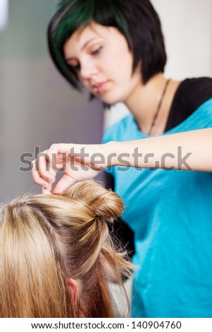 Young female hairdresser making client\'s hair in salon
