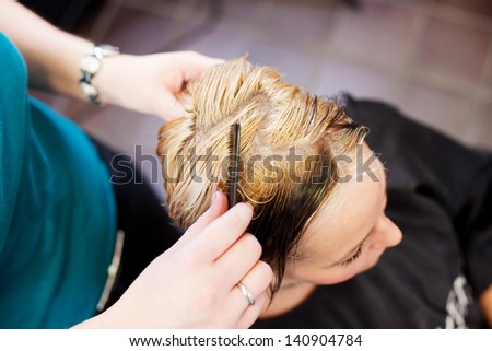 High angle view of hair dresser combing client\'s hair in salon