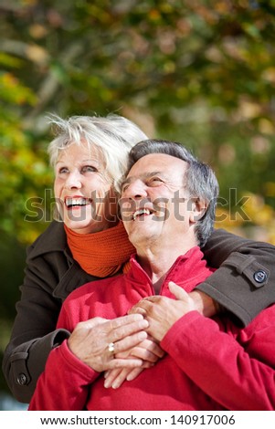 Portrait of senior woman embracing her husband at the back outdoors