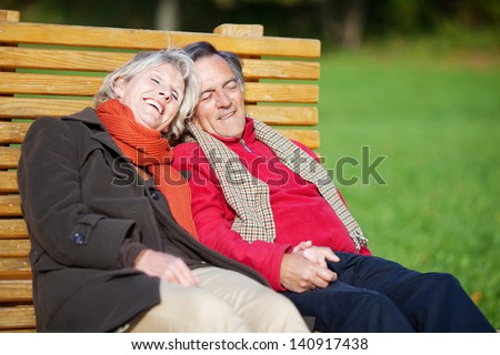 Senior couple enjoying the sun on a bench in a park