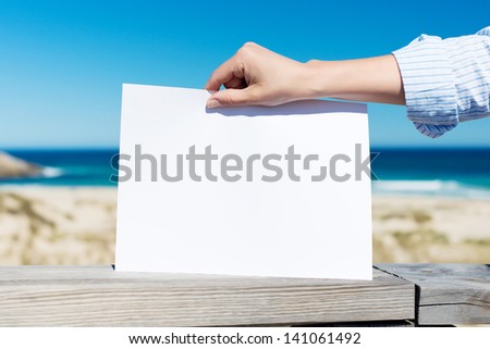 Closeup of woman\'s hand holding blank placard at beach