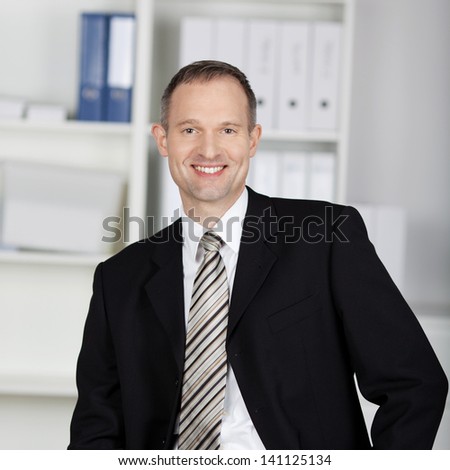 Handsome businessman in suit standing with office files background