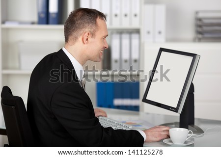 Smiling businessman working in front of computer at the office